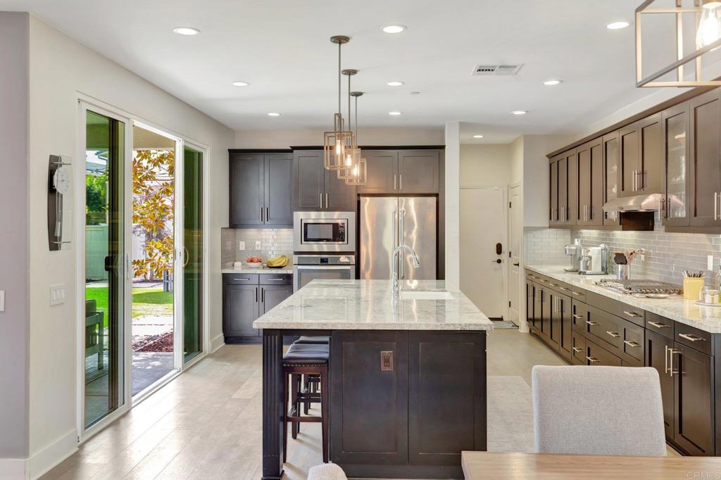 2954 Fledgling Drive Escondido, CA 92029 - Photo 12 of 49 a large kitchen with kitchen island a large counter top space a sink stainless steel appliances and cabinets