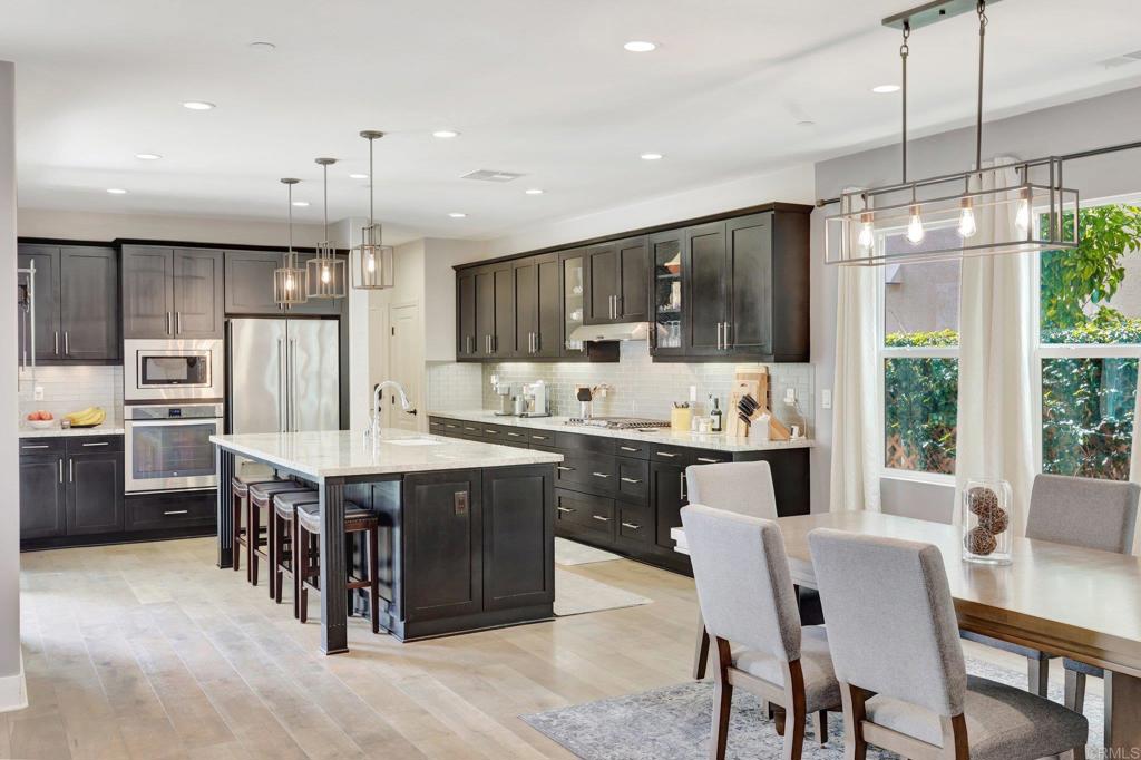 2954 Fledgling Drive Escondido, CA 92029 - Photo 10 of 49 a kitchen with stainless steel appliances granite countertop a sink a stove a refrigerator cabinets and a dining table
