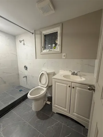 a bathroom with a granite countertop toilet sink and mirror