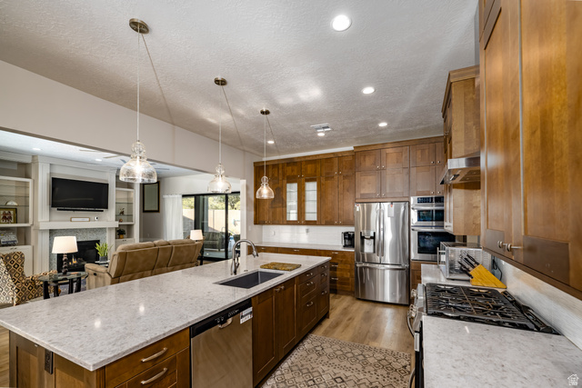 1283 North Gallen Road Santa Clara, UT 84765 - Photo 102 of 103 Kitchen featuring stainless steel appliances, open floor plan, a lit fireplace, hanging light fixtures, and light stone counters
