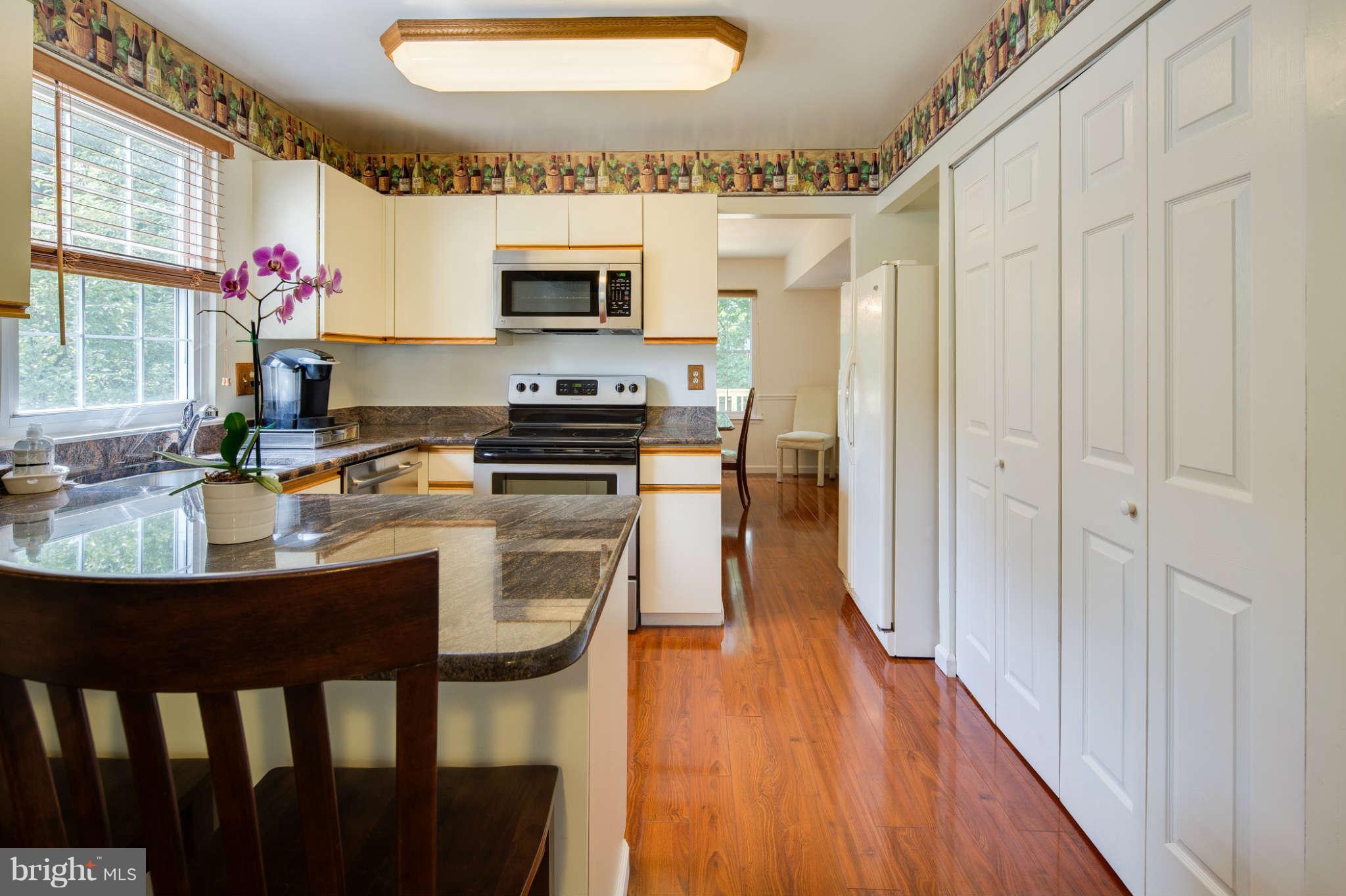 7330 Kindler Road Columbia, MD 21046 - Photo 10 of 28 a kitchen with stainless steel appliances a stove a sink dishwasher a microwave oven and a dining table with wooden floor