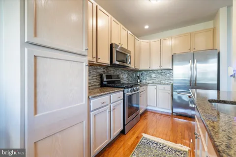 a kitchen with stainless steel appliances granite countertop a stove top oven a sink dishwasher a dining table and chairs with wooden floor