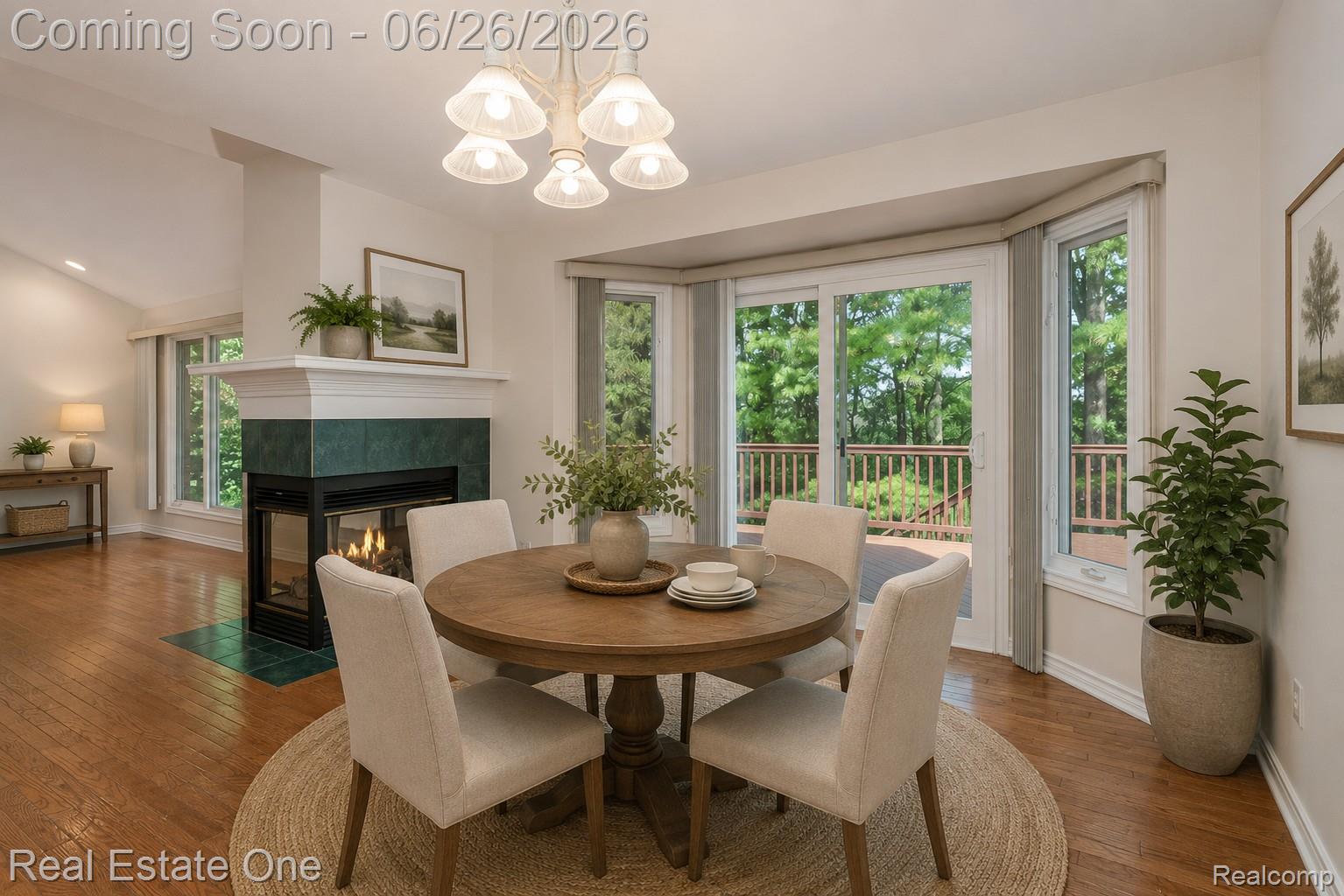 227 Bloomer Ridge Court Rochester, MI 48307 - Photo 10 of 45 Dining area featuring hardwood flooring, a gas fireplace with a green tiled surround, a chandelier, and sliding glass doors leading to an exterior deck