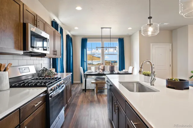 a kitchen with kitchen island granite countertop a sink a counter space appliances and cabinets