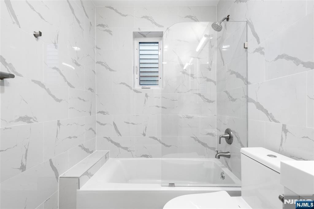 539 Undercliff Avenue, Unit 4 Edgewater, NJ 07020 - Photo 13 of 13 a bathroom with a white bath tub sitting next to a white sink and vanity
