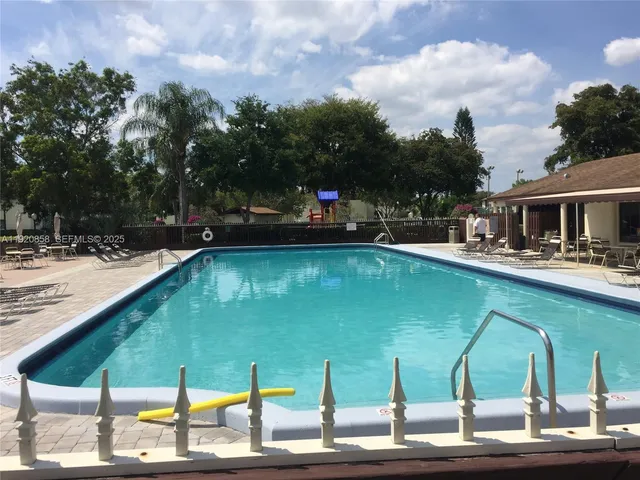 a view of a swimming pool with a lawn chairs under an umbrella