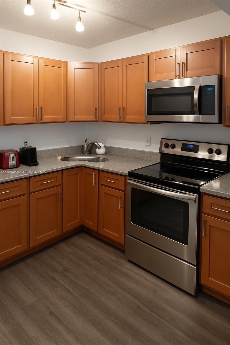 4717 Sable Pine Circle, Unit A2 West Palm Beach, FL 33417 - Photo 4 of 15 a kitchen with stainless steel appliances a stove a microwave and sink