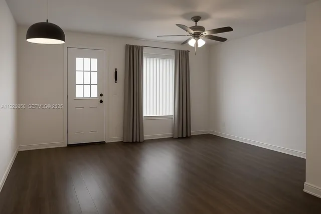 a view of an empty room with wooden floor and a window