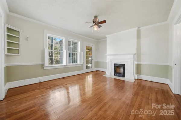 a view of an empty room with wooden floor fireplace and a window
