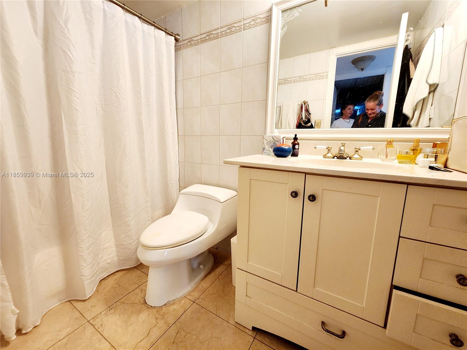 5555 Collins Avenue, Unit 9S Miami Beach, FL 33140 - Photo 11 of 48 a bathroom with a toilet sink and mirror