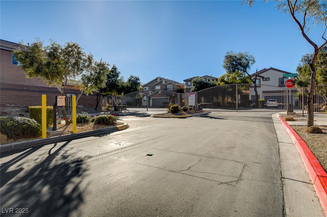 9310 Pinarello Street Las Vegas, NV 89178 - Photo 58 of 61 View of asphalt street with a gate, traffic signs, curbs, a gated entry, and a residential view
