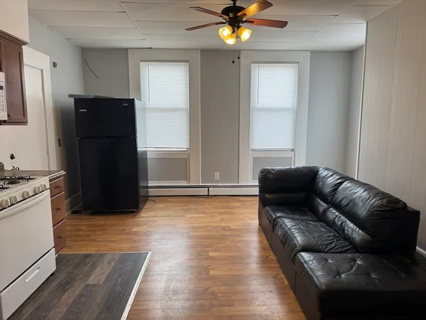 a living room with furniture and a refrigerator