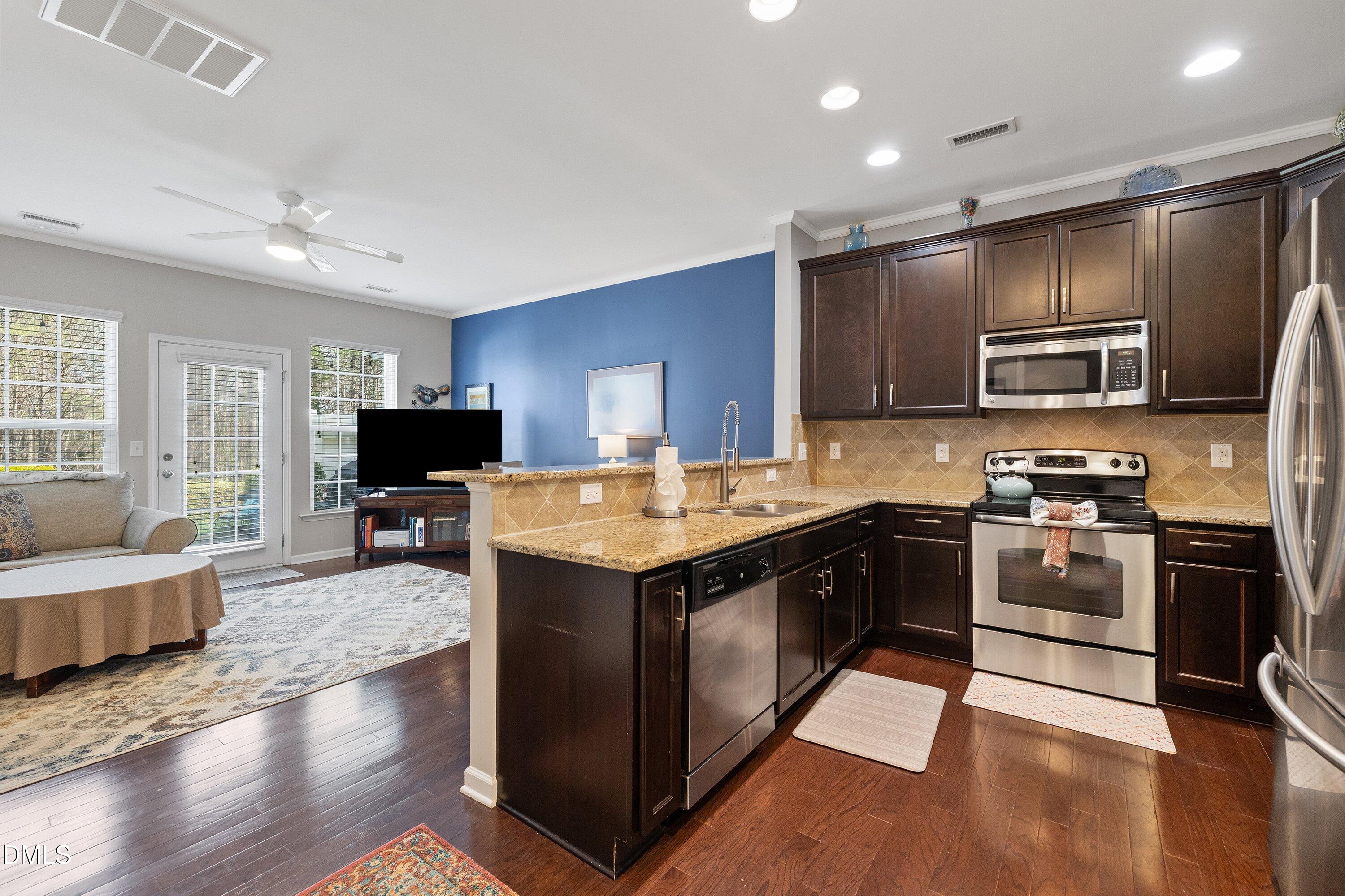 1093 Renewal Place Raleigh, NC 27603 - Photo 7 of 45 a large kitchen with stainless steel appliances granite countertop a stove top oven a sink dishwasher a dining table and chairs with wooden floor