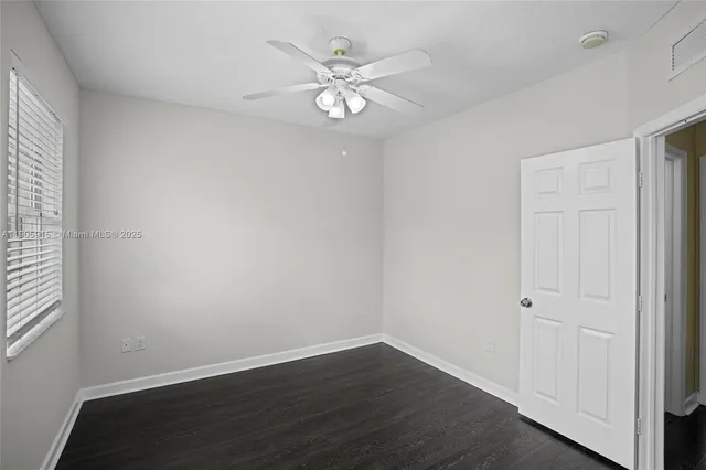 an empty room with wooden floor and ceiling fan