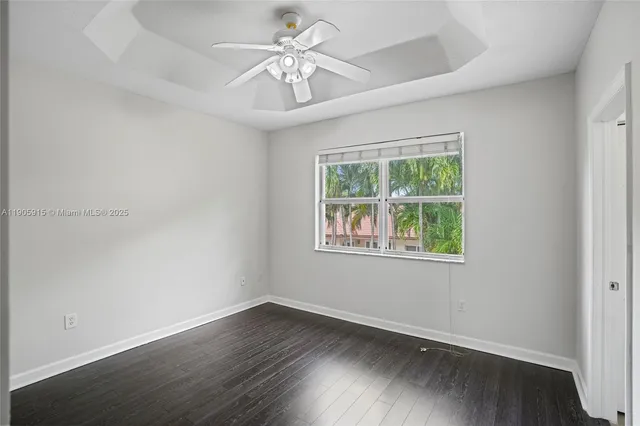 an empty room with wooden floor chandelier fan and windows