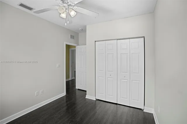an empty room with wooden floor closet fan and windows