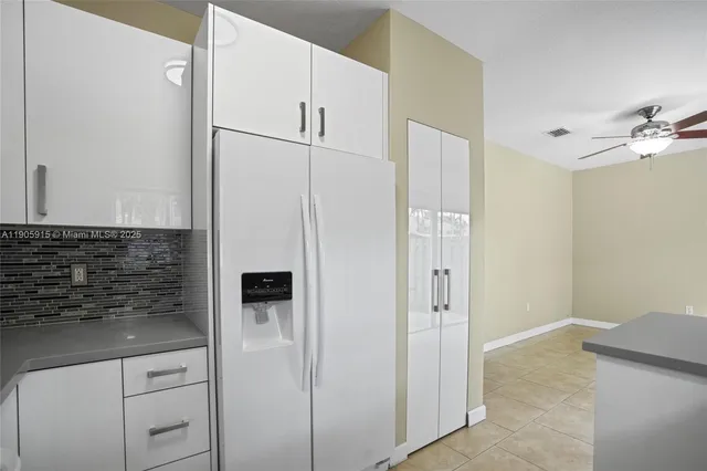 a view of a kitchen with white cabinets and refrigerator