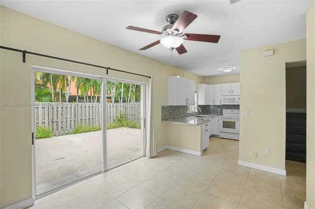 a view of a kitchen with a sink and dishwasher a refrigerator with white cabinets