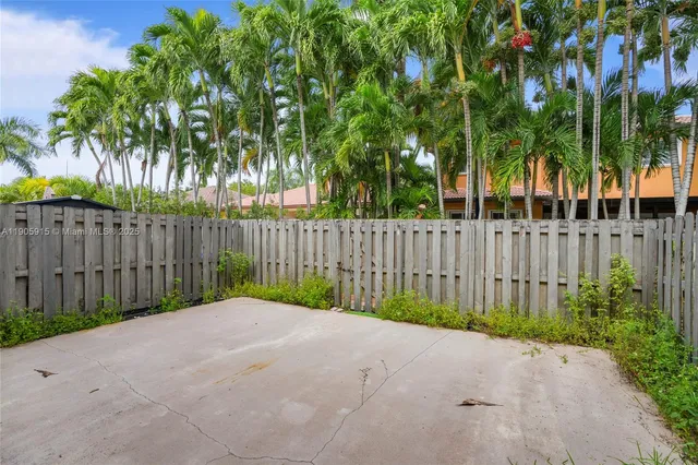 a view of a fence in front of a house with a small yard