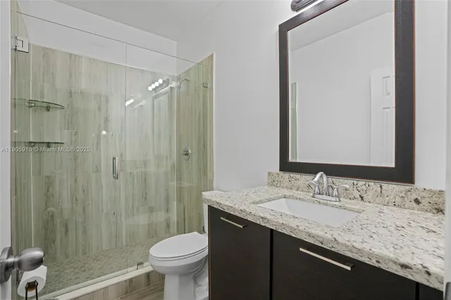 a bathroom with a granite countertop sink toilet and shower
