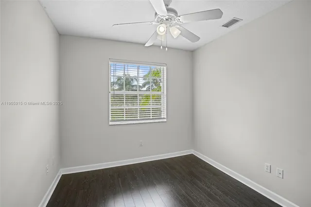 an empty room with wooden floor fan and windows