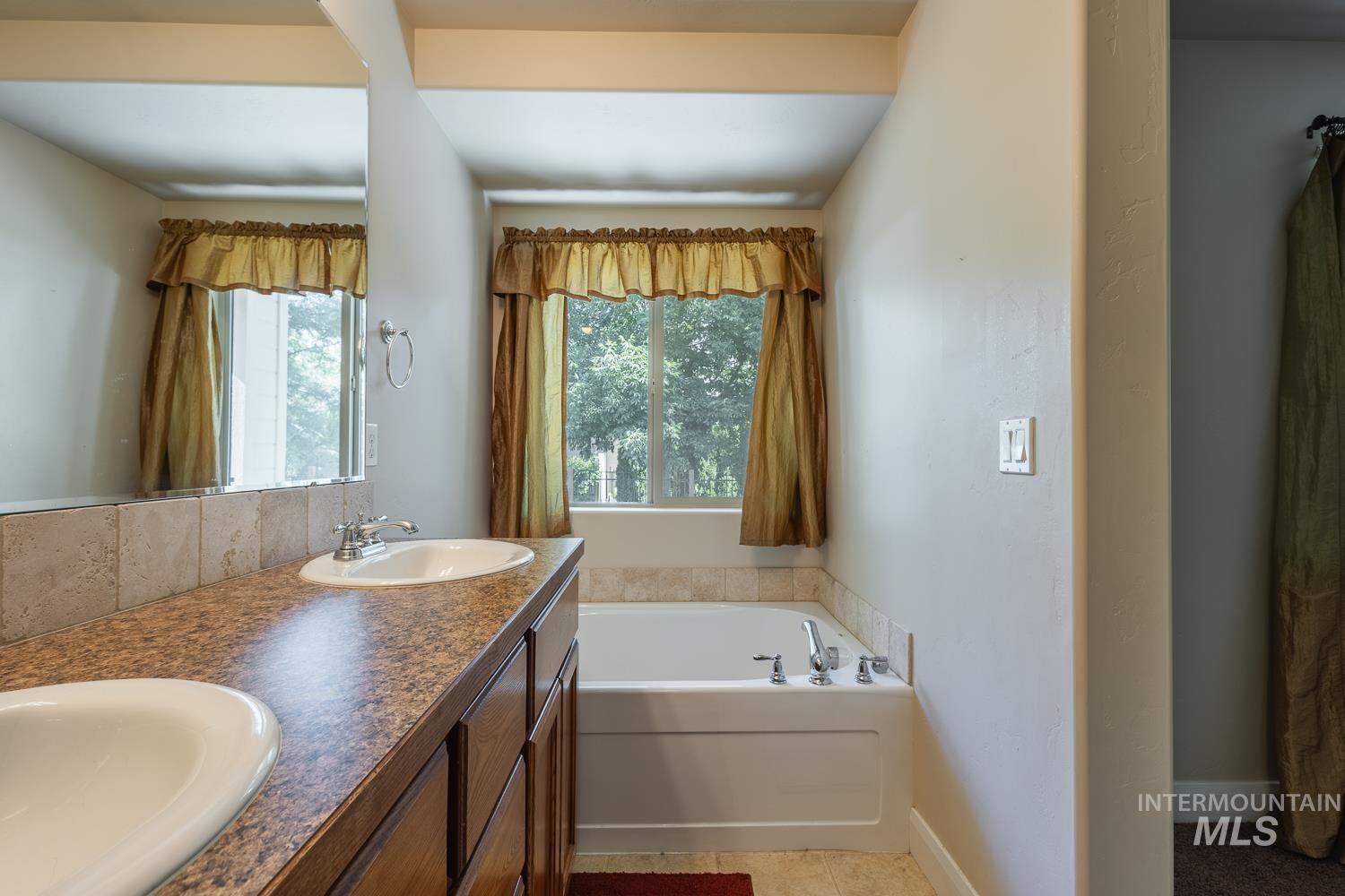 1186 East Observation Street Meridian, ID 83642 - Photo 24 of 33 Bathroom featuring a double vanity with integrated sinks, a speckled countertop, and a tiled backsplash
