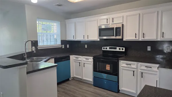 a kitchen with granite countertop white cabinets and black appliances