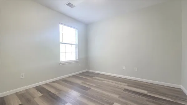 a view of a hallway with wooden floor and a window