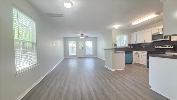 an empty room with wooden floor cabinet and windows