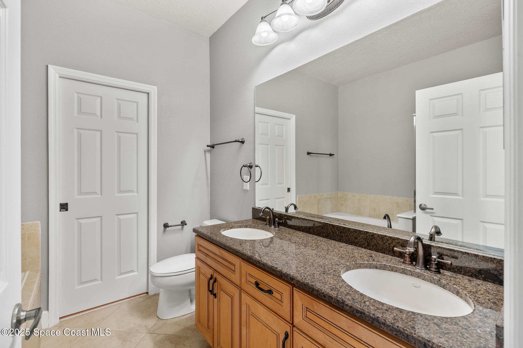 3126 Arden Circle Melbourne, FL 32934 - Photo 27 of 33 a bathroom with a granite countertop sink a toilet and a mirror