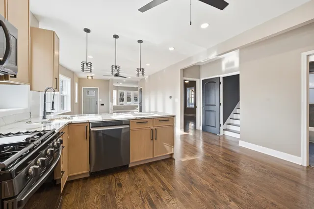a large kitchen with stainless steel appliances granite countertop a stove and a wooden floors