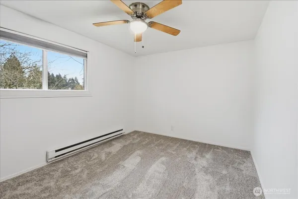 an empty room with a window and a fan