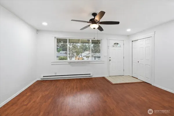 a view of empty room with wooden floor and fan