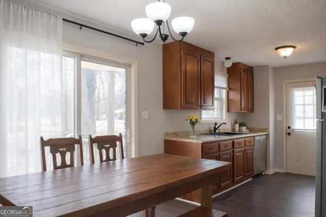 a dining room with wooden floor a chandelier a wooden table and chairs