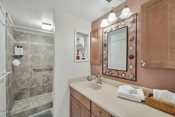 a bathroom with a granite countertop double vanity sink mirror and shower