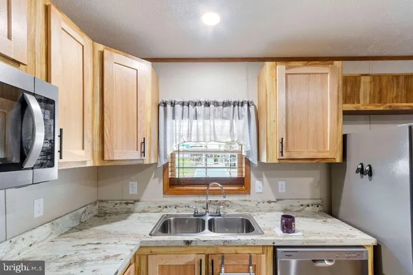 a kitchen with stainless steel appliances a sink a stove a refrigerator cabinets and a window