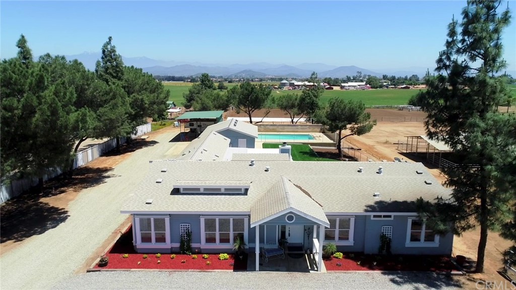an aerial view of a house with swimming pool and large trees