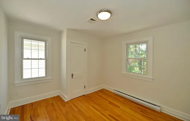 a view of a hallway with wooden floor and a bathroom