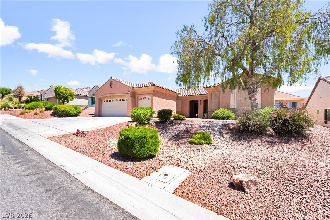 3033 Hartsville Road Henderson, NV 89052 - Photo 5 of 41 An inviting exterior with a well-maintained xeriscaped front yard, showcasing a two-car garage and mature tree.