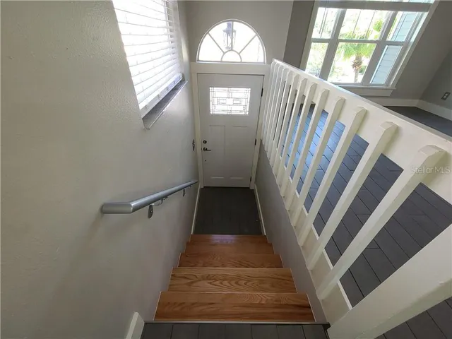 an empty room with wooden floor a fireplace a chandelier and windows