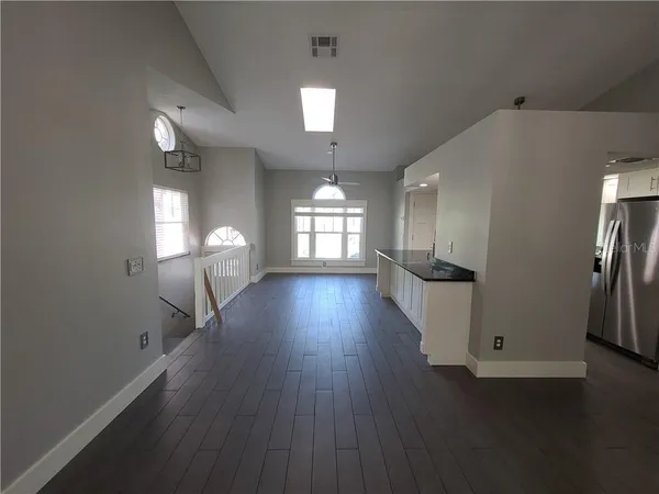 a view of a livingroom with a fireplace a ceiling fan and windows