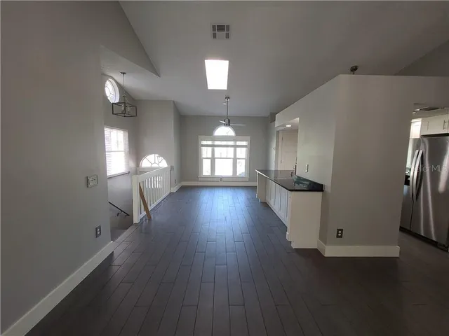a view of a livingroom with a fireplace a ceiling fan and windows