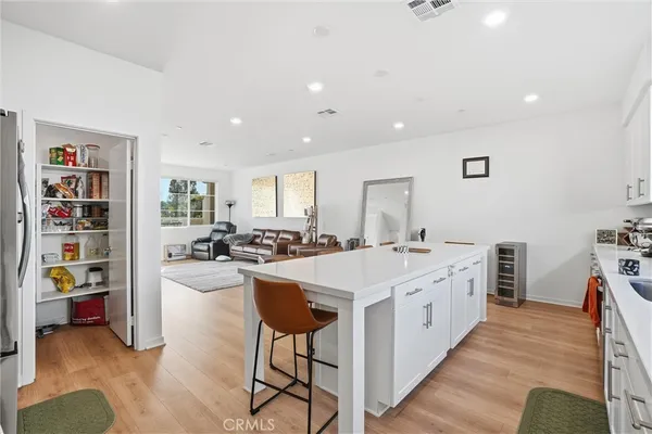 a large white kitchen with a stove a sink dishwasher and a dining table with wooden floor