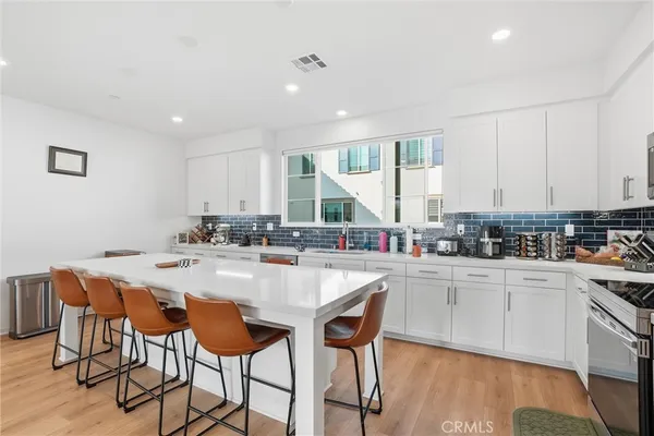 a kitchen with stainless steel appliances granite countertop a table chairs sink and cabinets