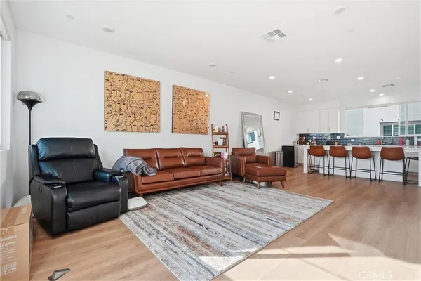 a living room with furniture kitchen view and a wooden floor