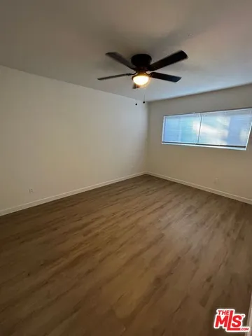 an empty room with a ceiling fan and wooden floor