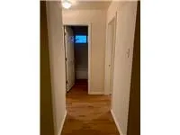 a view of a hallway with a white door and a refrigerator
