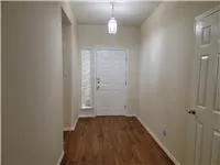 a view of a hallway with wooden floor and a chandelier