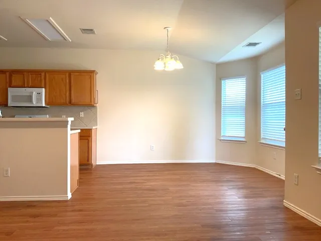 a view of a kitchen with wooden floor and a refrigerator
