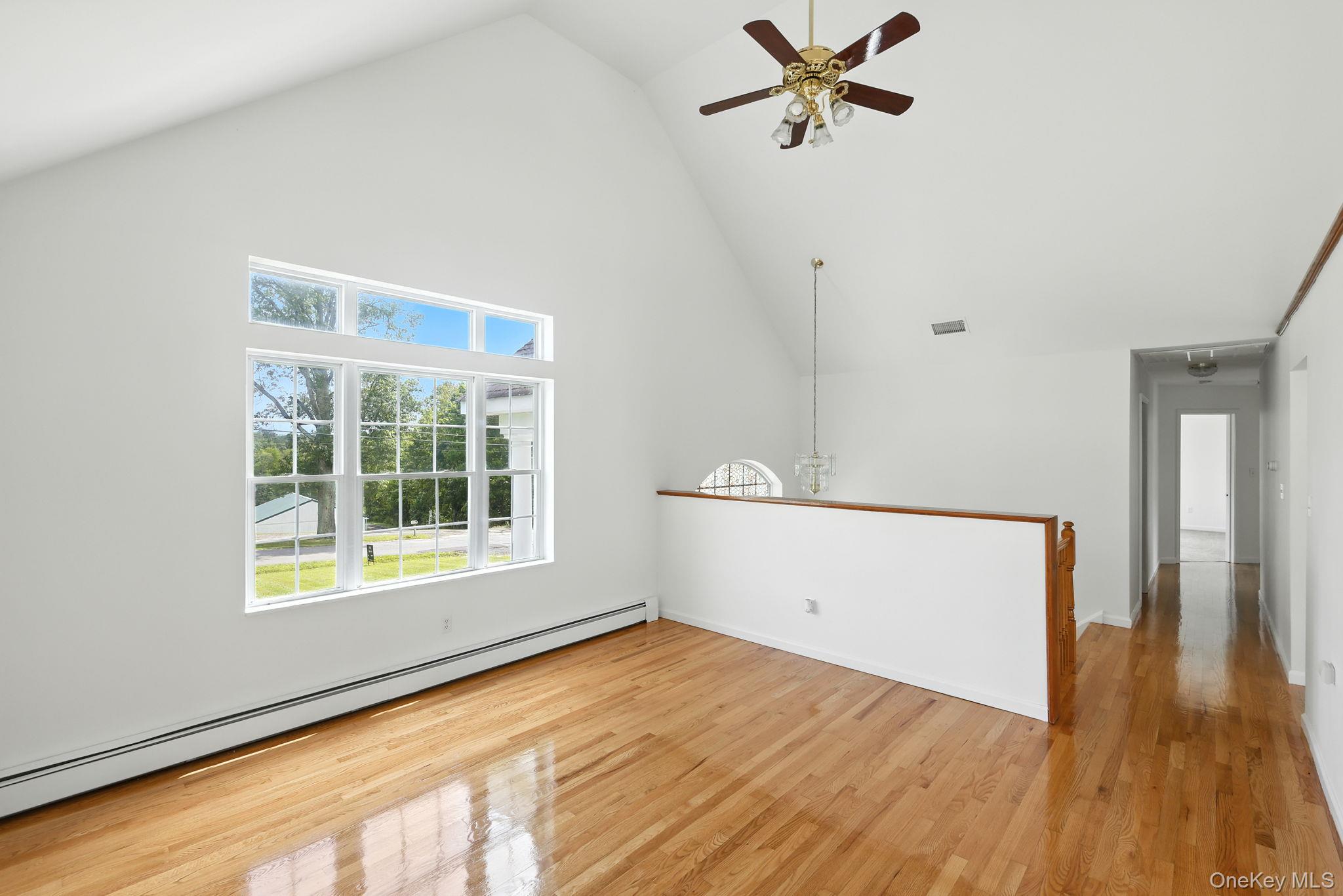 160 Pirog Road Pine Bush, NY 12566 - Photo 8 of 26 Spare room featuring baseboard heating, high vaulted ceiling, a ceiling fan, and light wood-type flooring